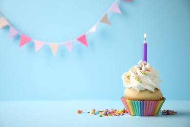 Photo of Delicious birthday cupcake with candle on light blue background. Space for text