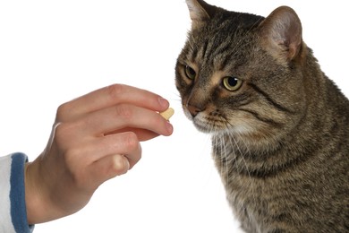 Photo of Woman giving heart shaped pill to cute cat on white background, closeup. Vitamins for animal