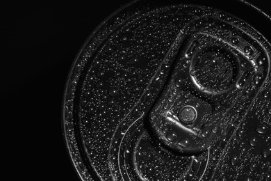 Photo of Aluminum can of beverage covered with water drops on black background, top view