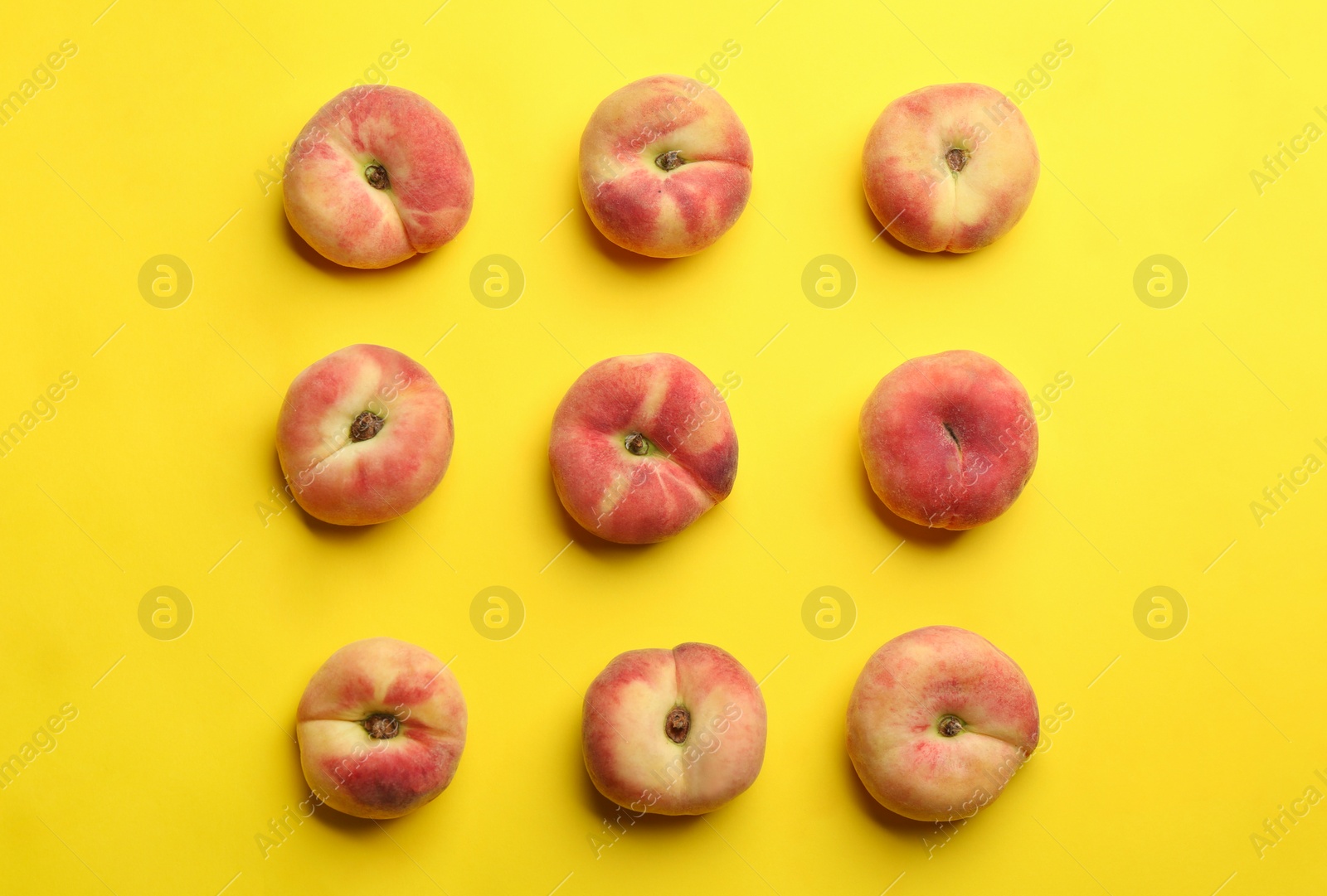 Photo of Fresh donut peaches on yellow background, flat lay