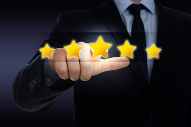 Image of Quality evaluation. Businessman touching virtual golden star on dark background, closeup