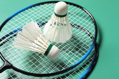 Photo of Feather badminton shuttlecocks and rackets on green background, closeup