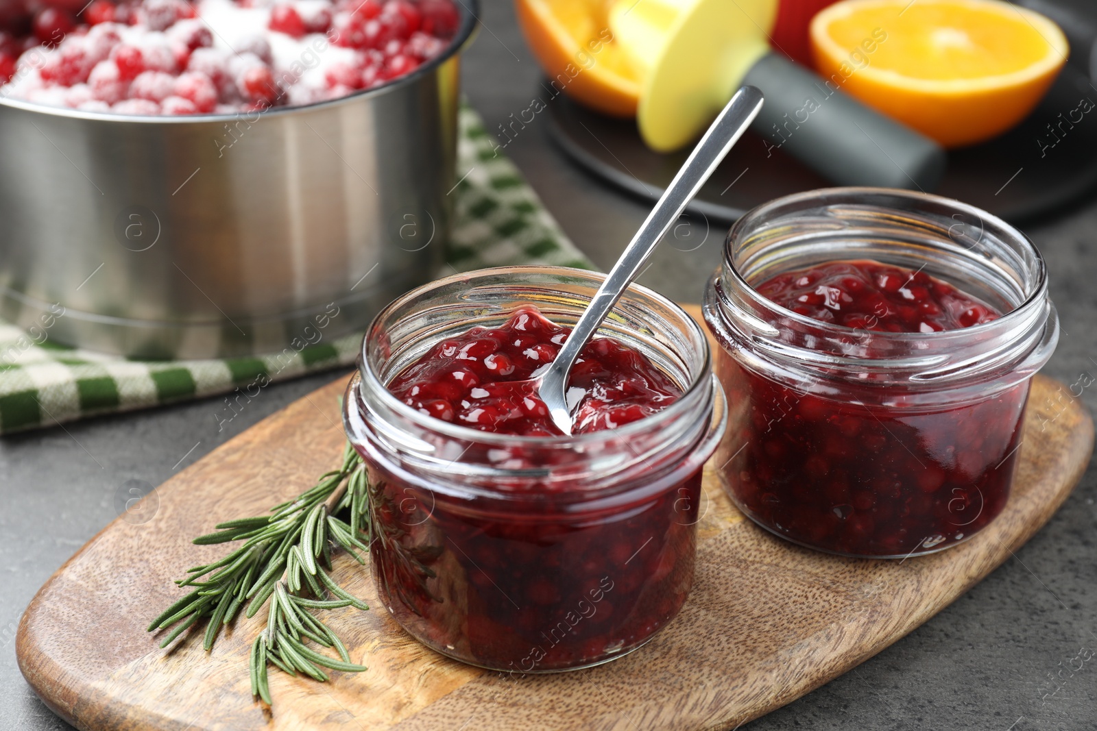Photo of Fresh cranberry sauce in glass jars served on gray table, closeup