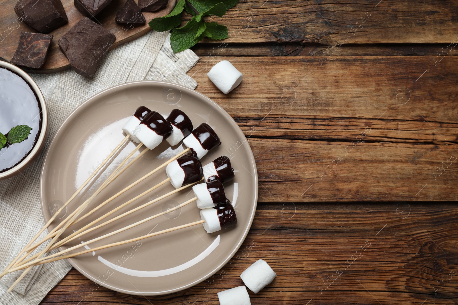 Photo of Delicious marshmallows covered with chocolate on wooden table, flat lay. Space for text