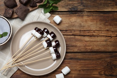 Delicious marshmallows covered with chocolate on wooden table, flat lay. Space for text