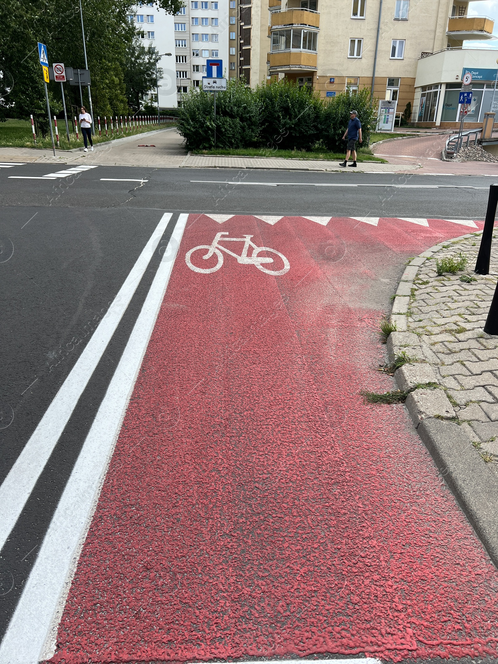 Photo of Warsaw, Poland - July 18, 2022: Red bicycle lane with white sign painted on asphalt in city