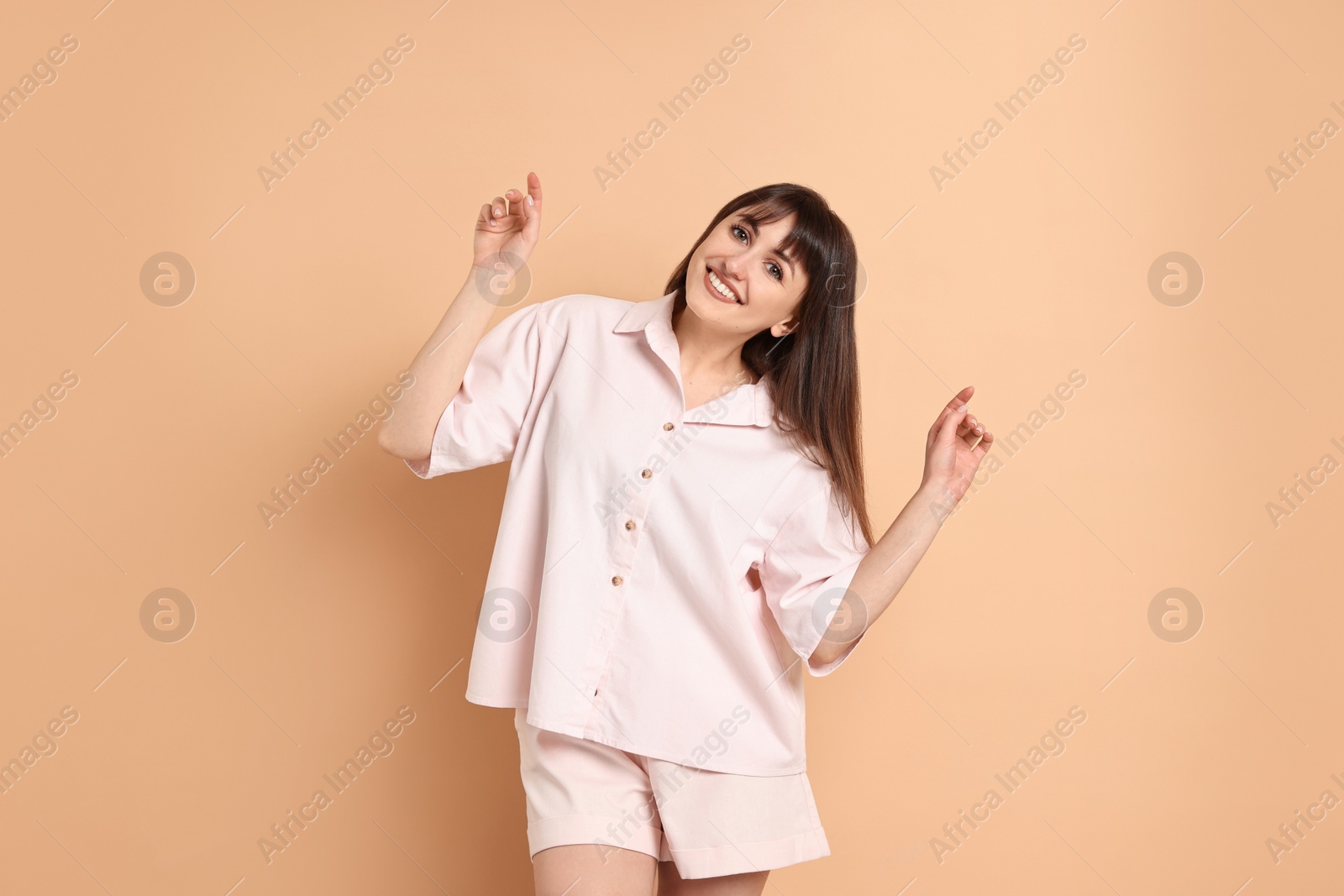 Photo of Happy woman wearing pyjama on beige background