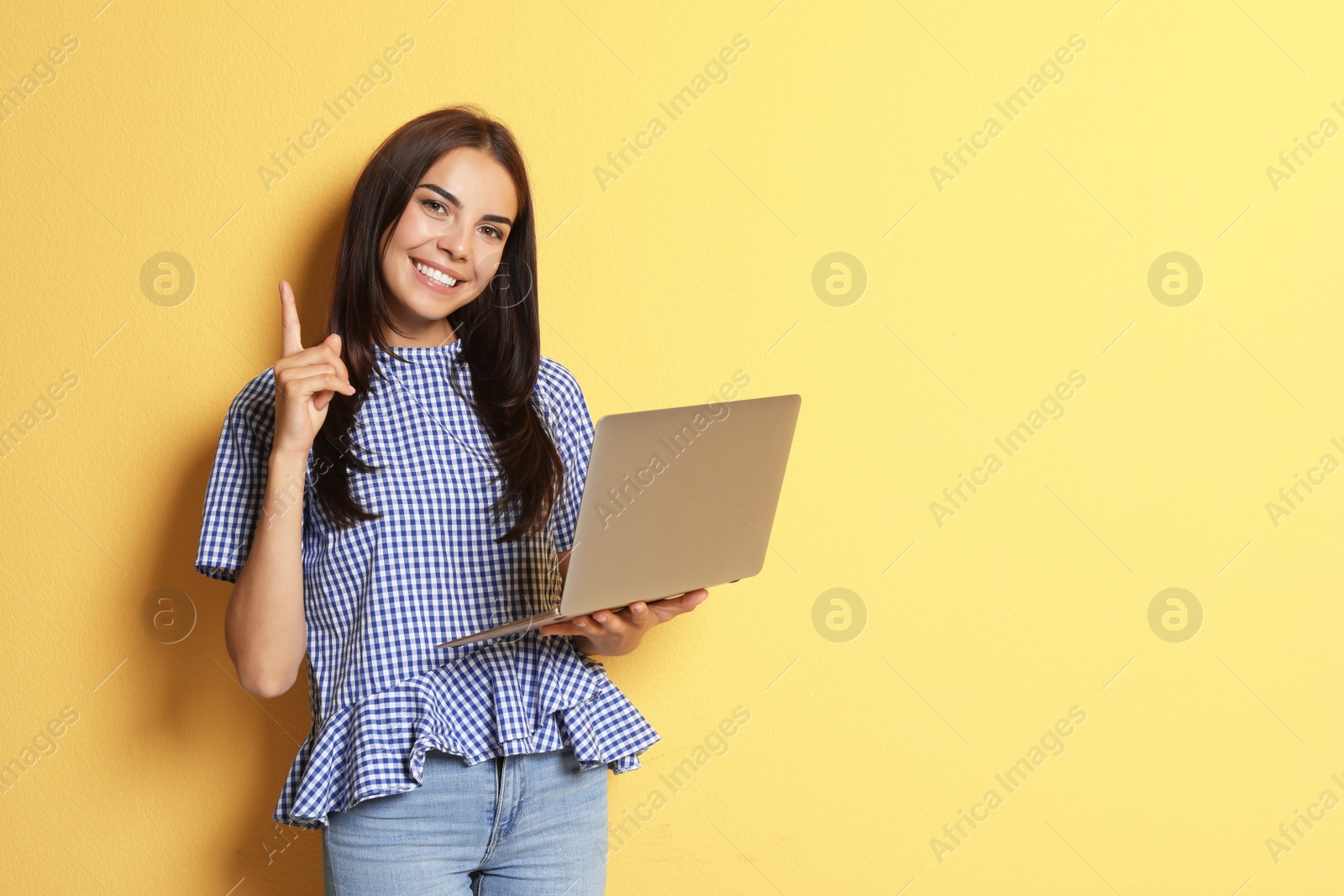 Photo of Young woman with modern laptop on color background