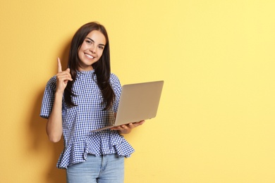 Young woman with modern laptop on color background