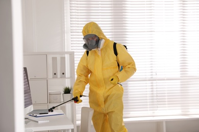 Photo of Man in protective suit sanitizing doctor's office. Medical disinfection