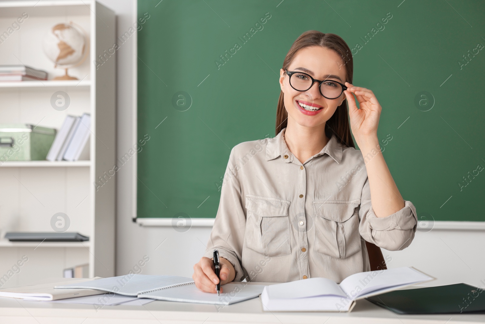 Photo of Portrait of beautiful young teacher at table in classroom