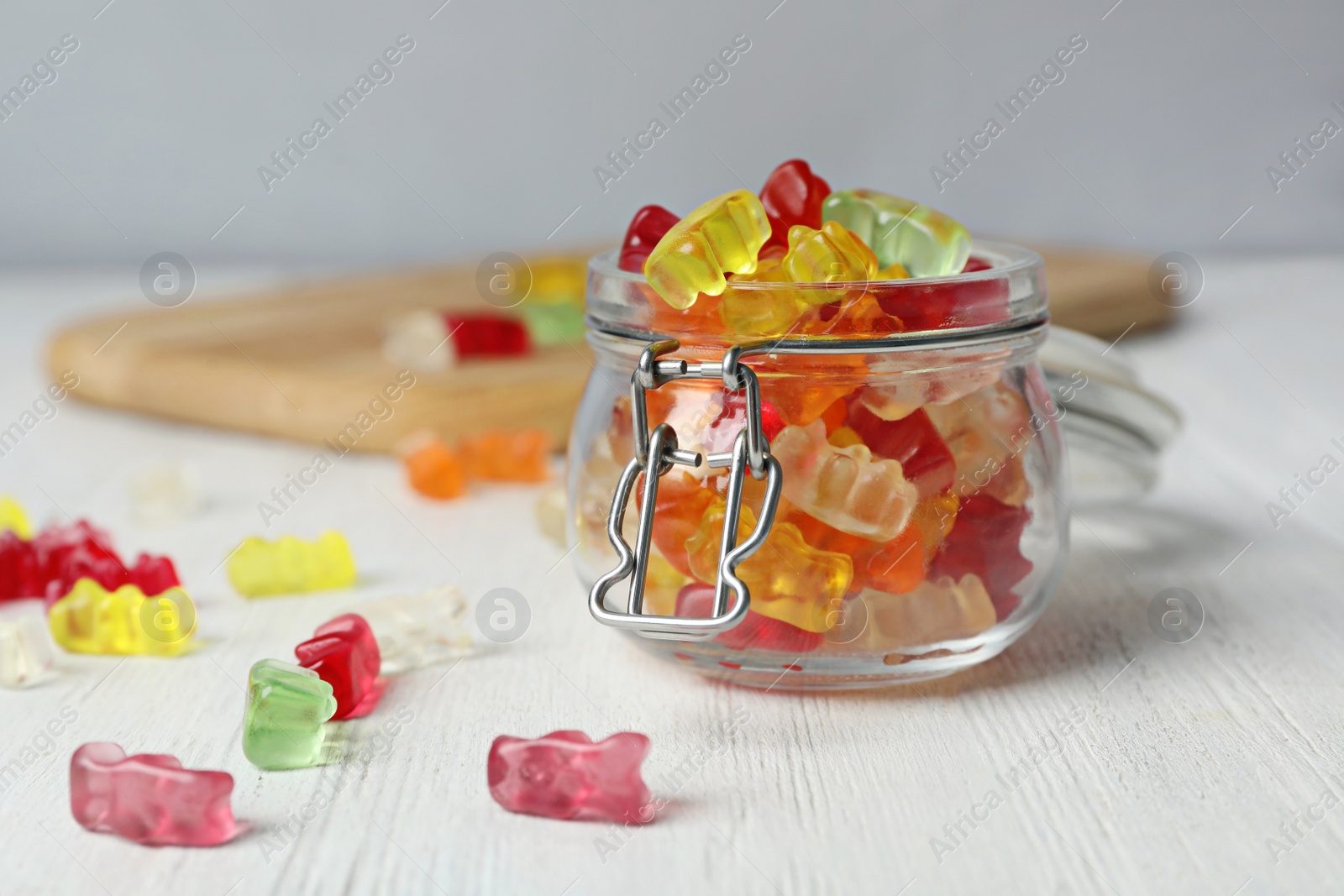 Photo of Delicious jelly bears in glass jar on wooden table. Space for text