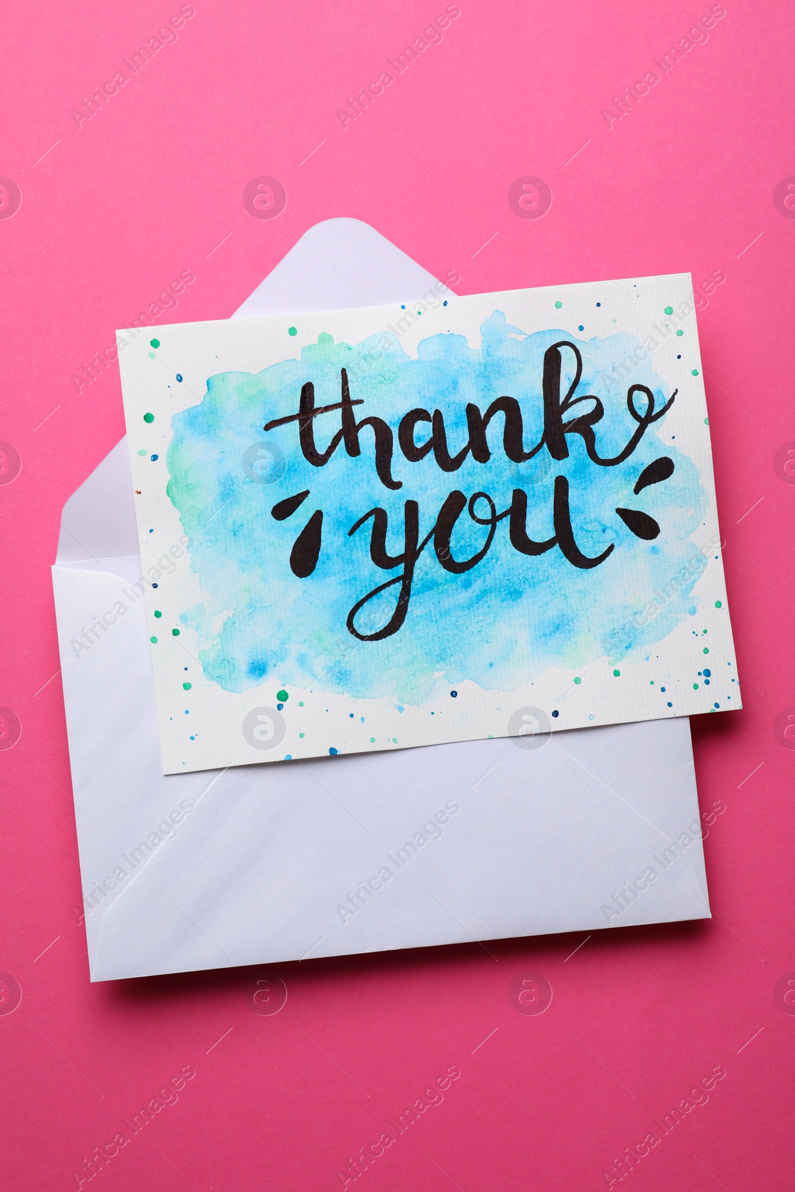 Photo of Envelope and card with phrase Thank You on pink background, top view