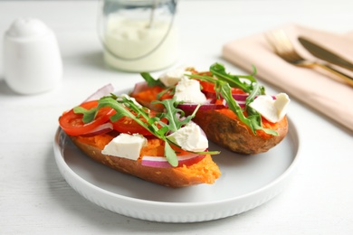 Plate with stuffed sweet potatoes on white wooden table