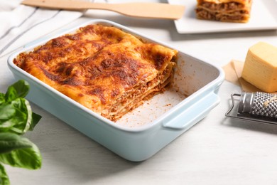Photo of Delicious lasagna in baking dish on white table