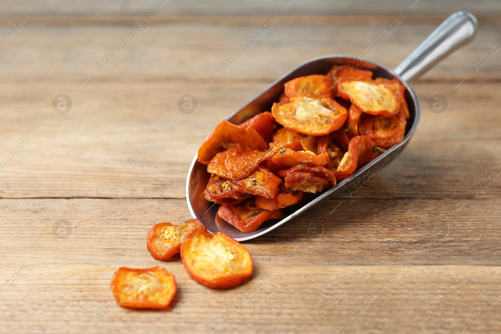 Photo of Scoop with cut dried kumquat fruits on wooden table, closeup