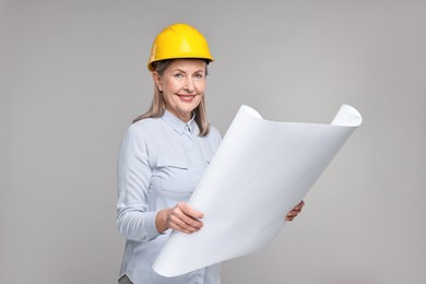 Architect in hard hat with draft on grey background