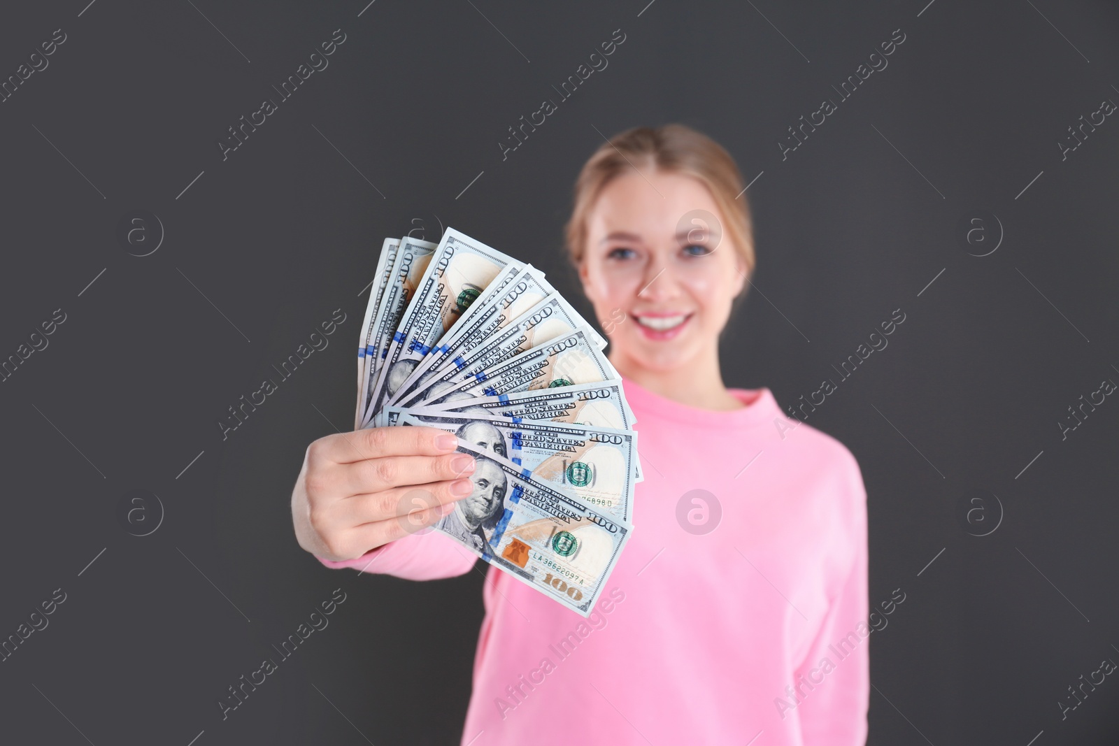 Photo of Portrait of happy young woman with money on grey background