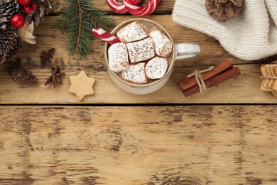 Flat lay composition with delicious marshmallow cocoa and Christmas decor on wooden table. Space for text