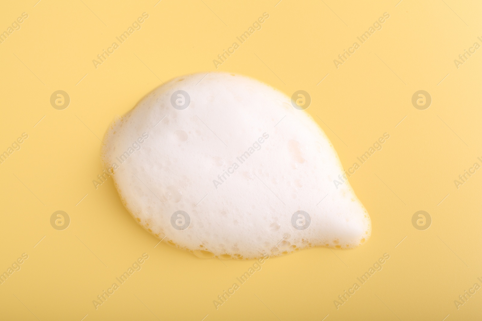 Photo of Sample of fluffy foam on yellow background, top view