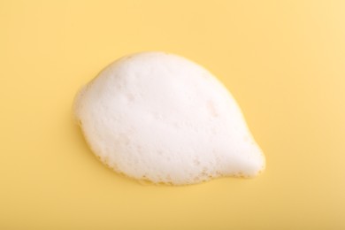 Sample of fluffy foam on yellow background, top view