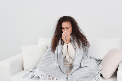 Photo of Sick African American woman with tissue at home