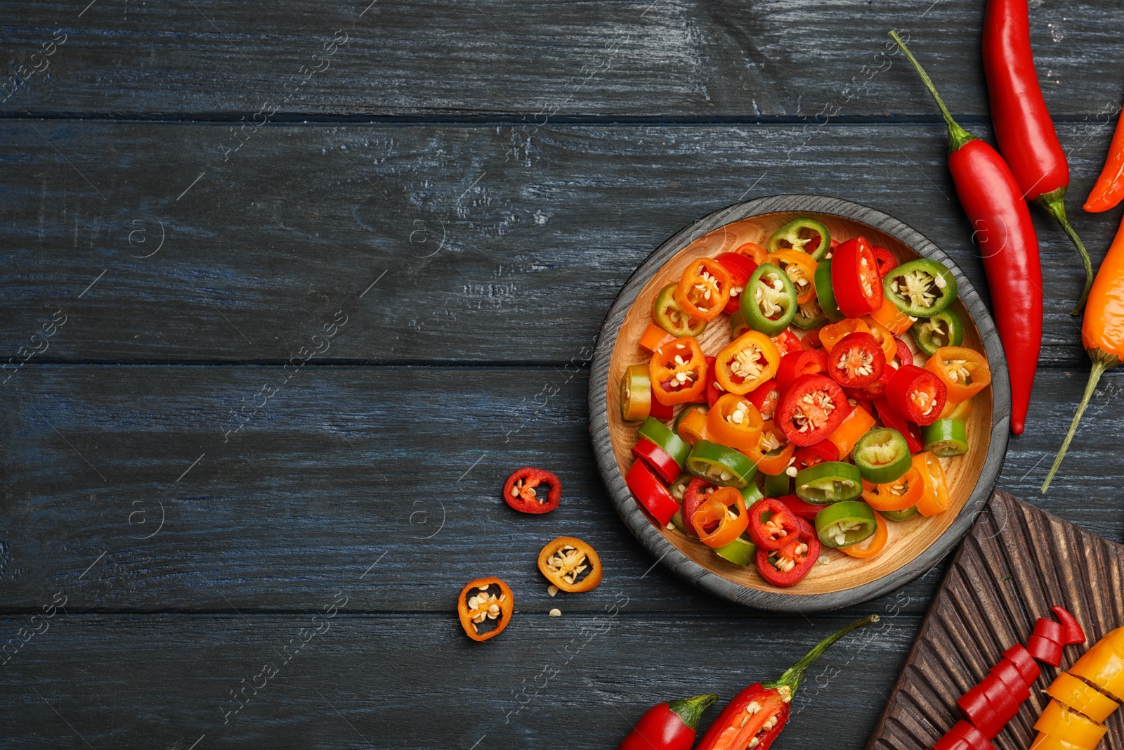 Photo of Flat lay composition with different hot chili peppers on grey wooden table. Space for text