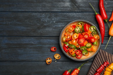 Flat lay composition with different hot chili peppers on grey wooden table. Space for text