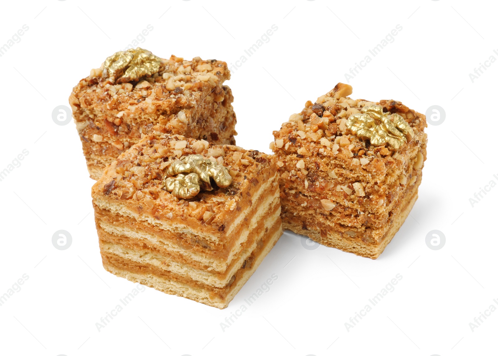 Photo of Pieces of layered honey cake with walnuts on white background