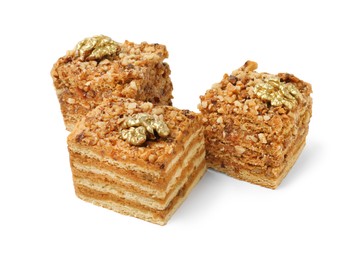 Photo of Pieces of layered honey cake with walnuts on white background