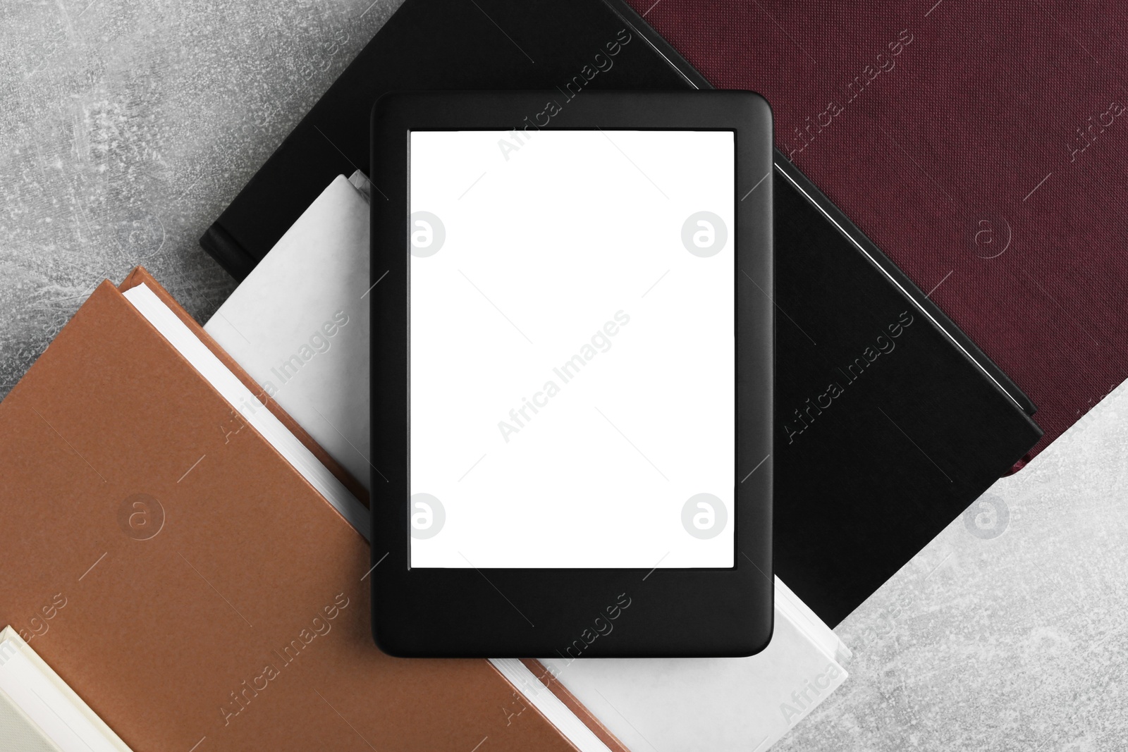 Photo of Portable e-book reader on hardcover books on grey textured table, flat lay