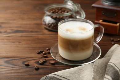 Photo of Aromatic coffee in cup and beans on wooden table, space for text