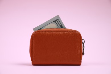 Photo of Stylish brown leather purse with dollar banknote on pink background