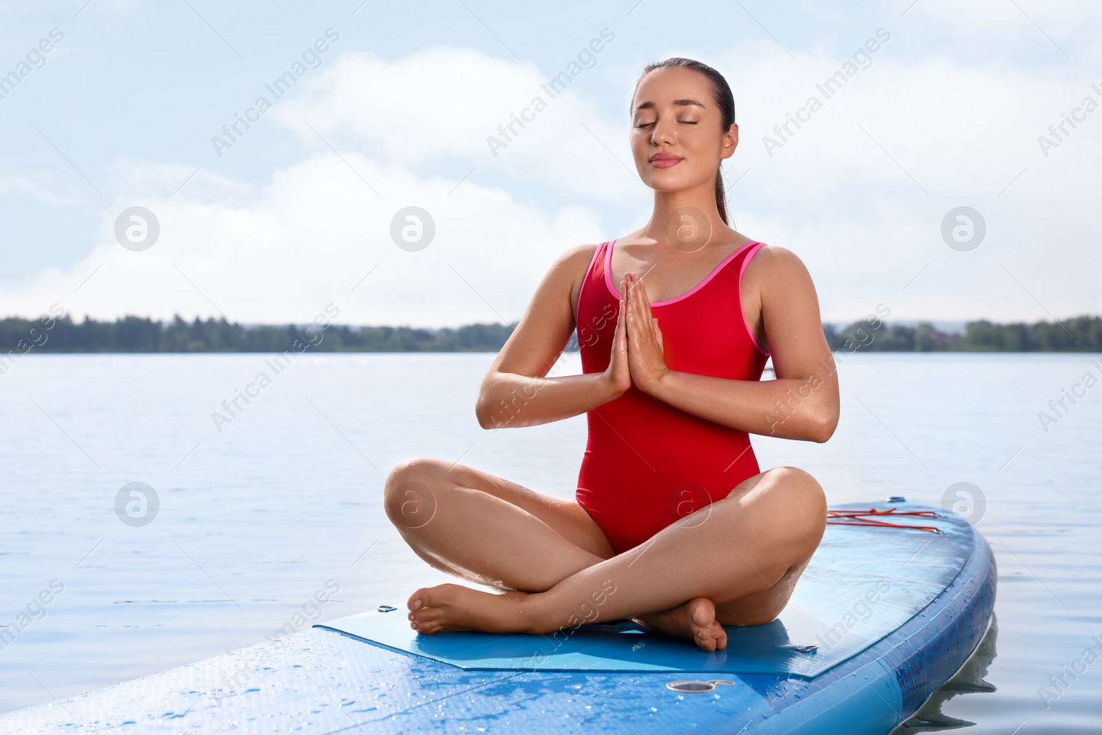 Photo of Woman practicing yoga on light blue SUP board on river