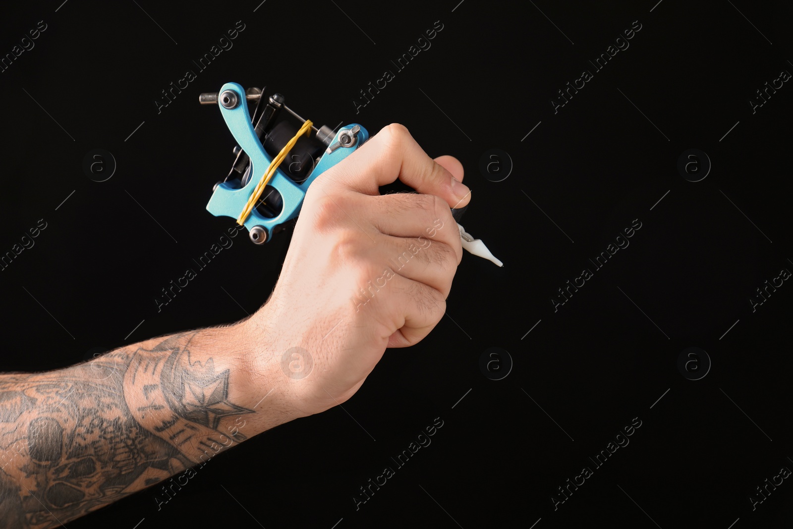 Photo of Professional tattoo artist with machine on black background, closeup. Space for text