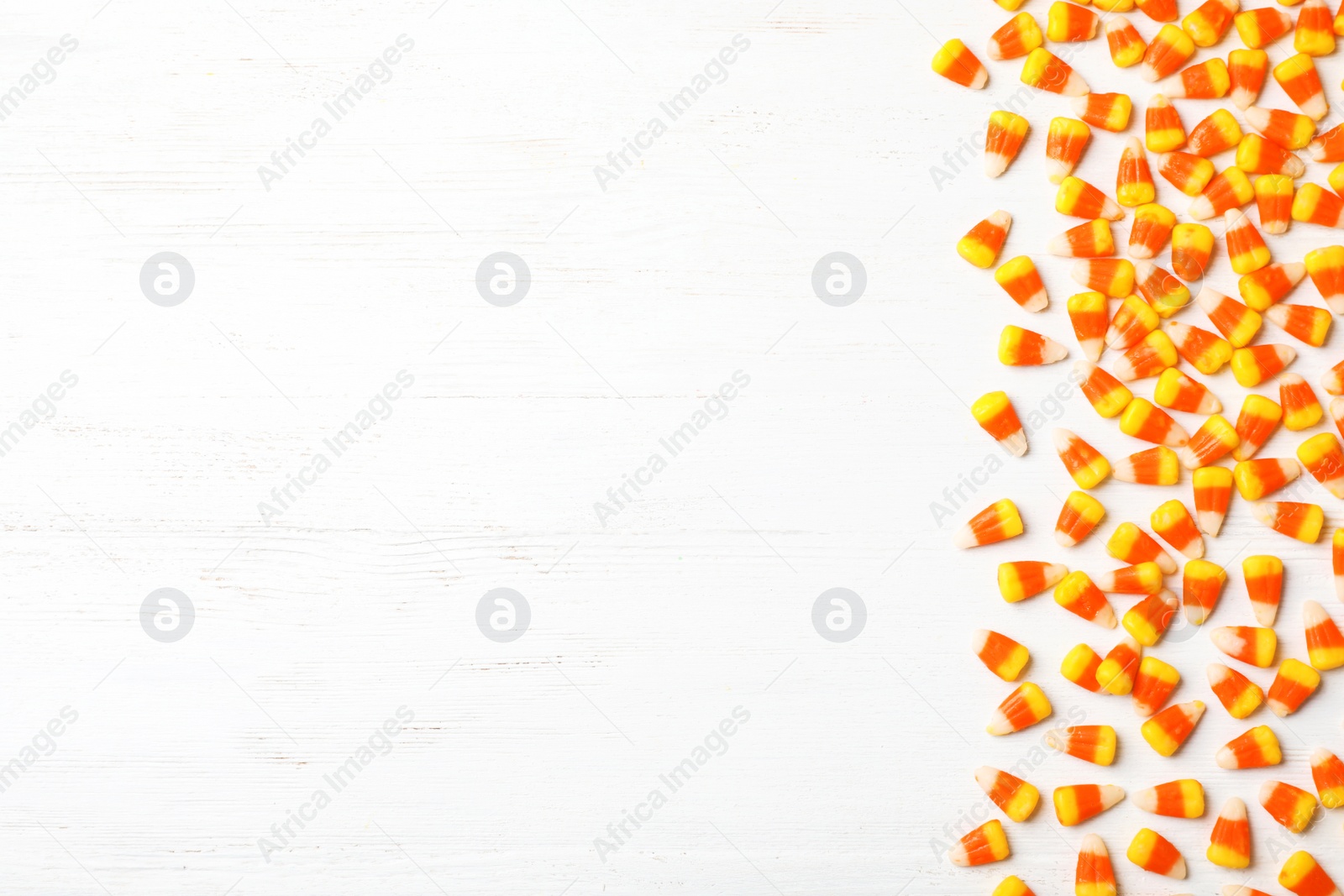 Photo of Flat lay composition with delicious candy corns and space for text on wooden background