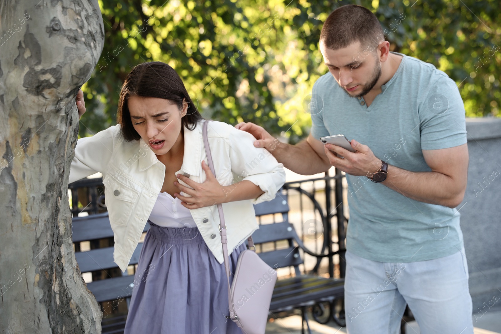 Photo of Man calling ambulance to help woman with heart attack in park