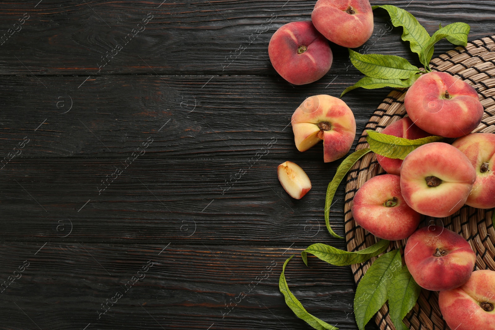Photo of Fresh ripe donut peaches on black wooden table, flat lay. Space for text