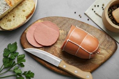 Photo of Board with tasty boiled sausage on light grey textured table, flat lay