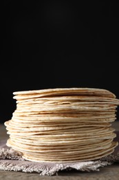 Many tasty homemade tortillas on wooden table, space for text