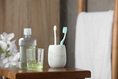 Photo of Mouthwash and toothbrushes on wooden table in bathroom