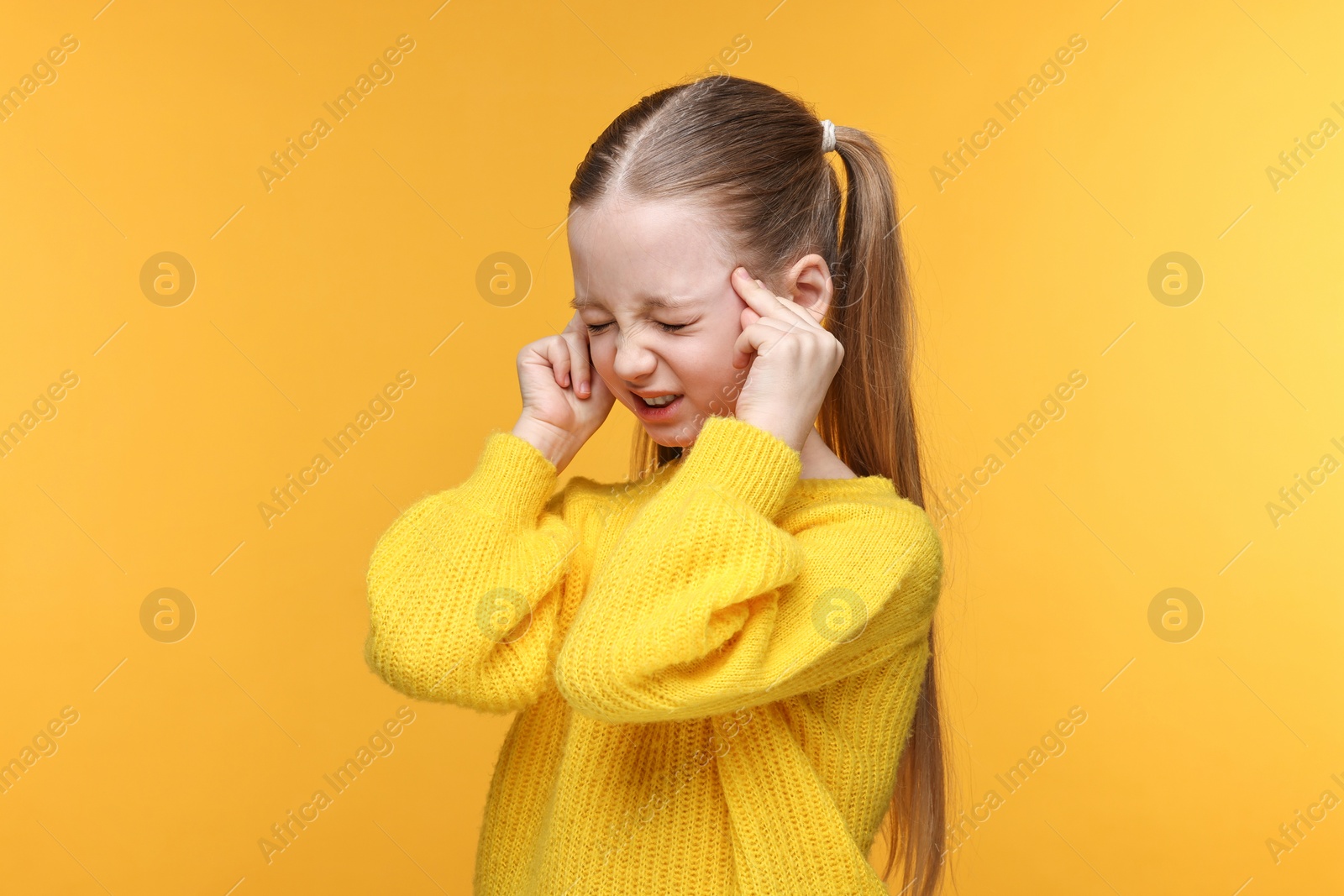 Photo of Little girl suffering from headache on yellow background