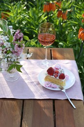 Photo of Vase with spring flowers, wine and cake on table served for romantic date in garden