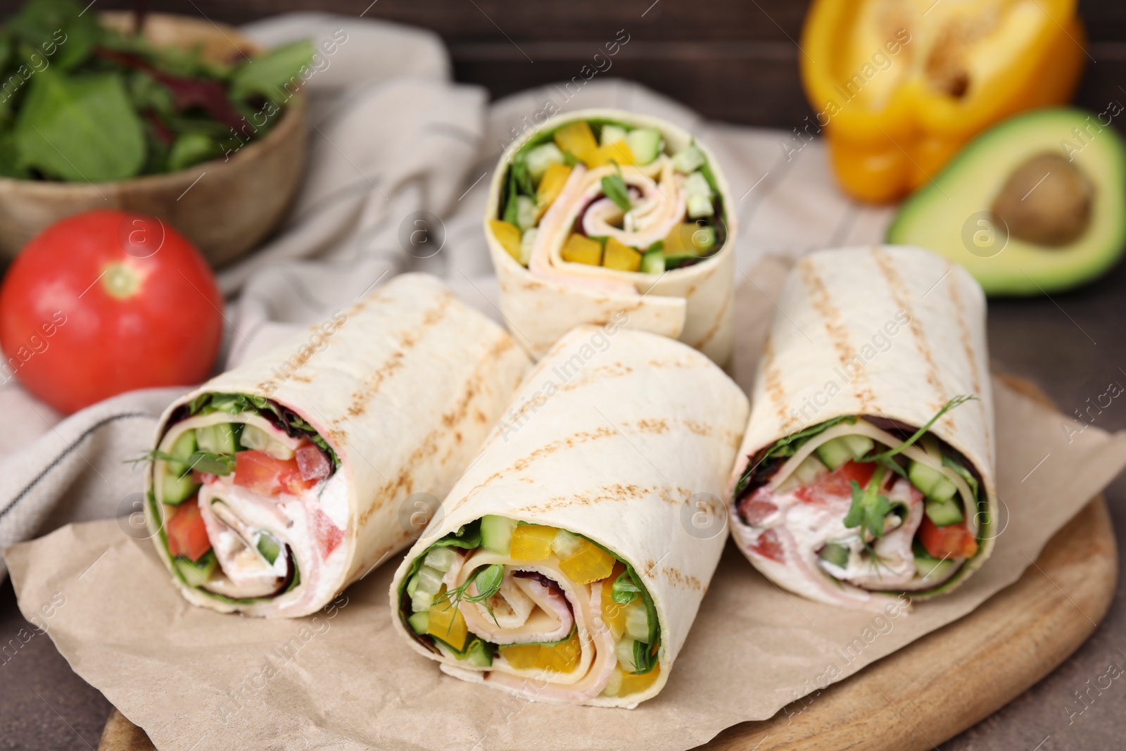 Photo of Delicious sandwich wraps with fresh vegetables on wooden board, closeup