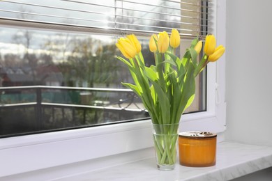 Photo of Wonderful tulips and candle on window sill indoors, space for text. Spring atmosphere