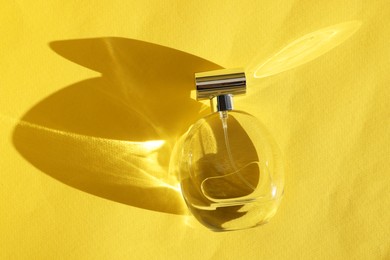 Luxury women's perfume in bottle on yellow background, top view. Space for text