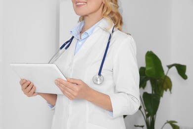 Doctor with tablet and stethoscope in clinic, closeup. Online medicine concept