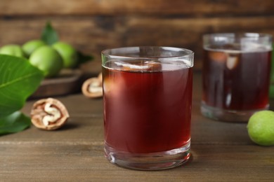 Photo of Delicious liqueur with ice and fresh walnuts on wooden table