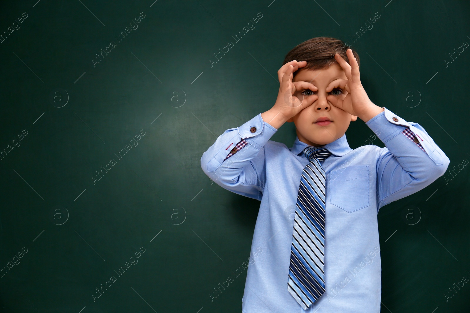 Photo of Funny little child near chalkboard, space for text. First time at school