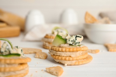 Photo of Delicious crackers with humus and cucumber on white wooden table, closeup